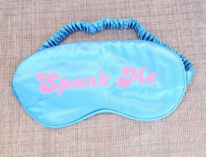 blue silk eye mask with pink text that says Spank Me