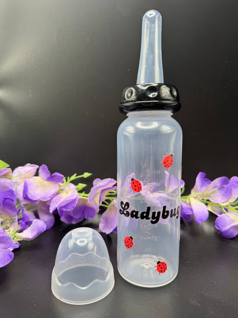 ABDL bottle with long nipple and black top. Ladybugs surrounding the text Ladybug