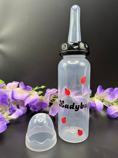 ABDL bottle with long nipple and black top. Ladybugs surrounding the text Ladybug