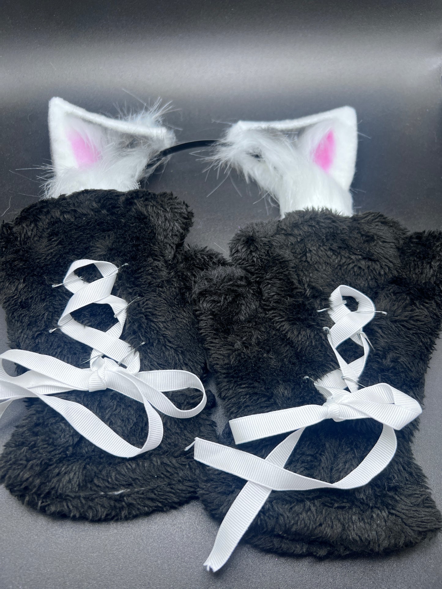 back view of black costume paw gloves with white ribbon corset and matching ears