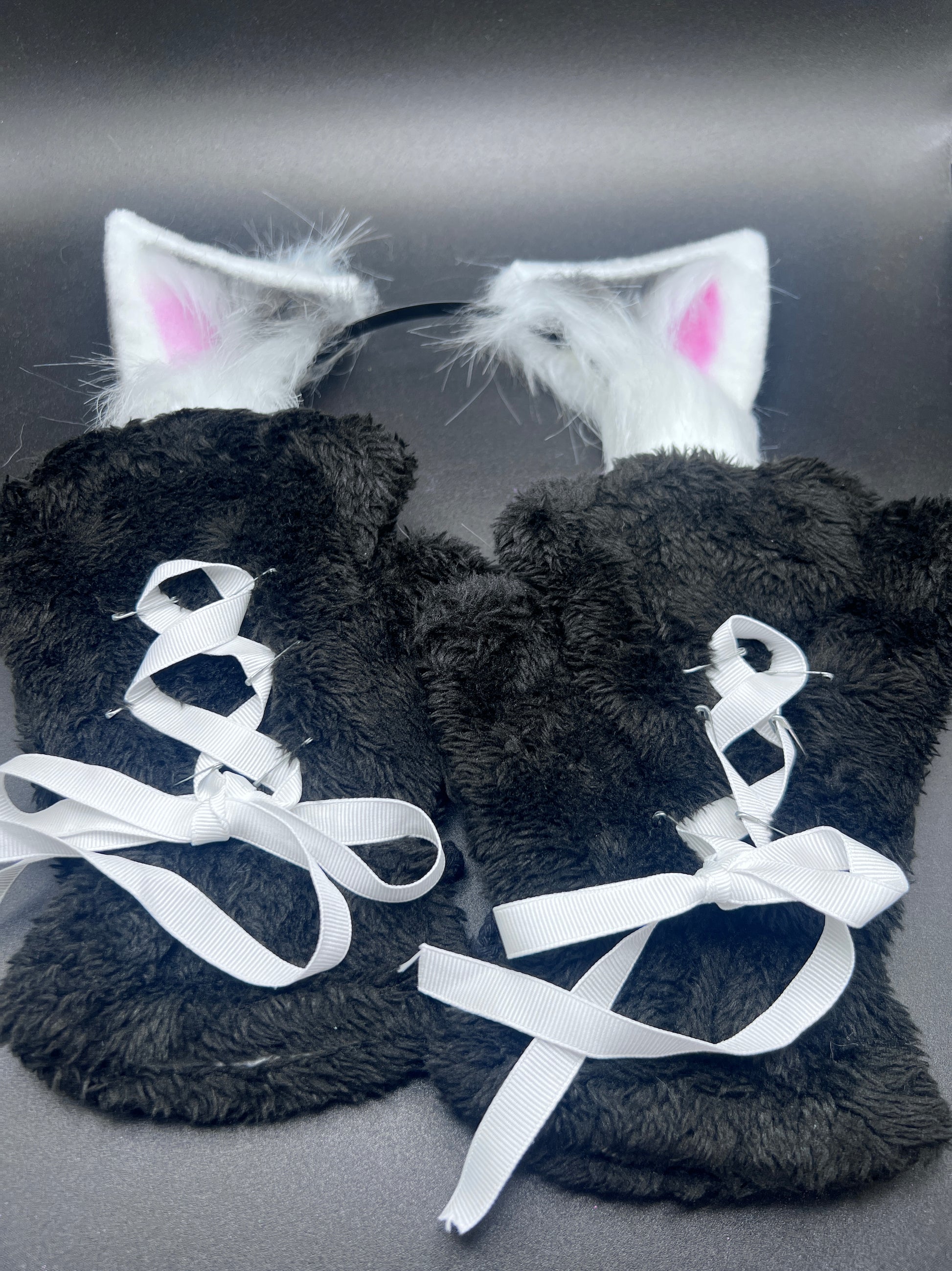 back view of black costume paw gloves with white ribbon corset and matching ears