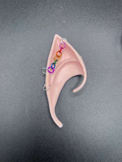 Tan elf ear with rainbow chain on a gray background