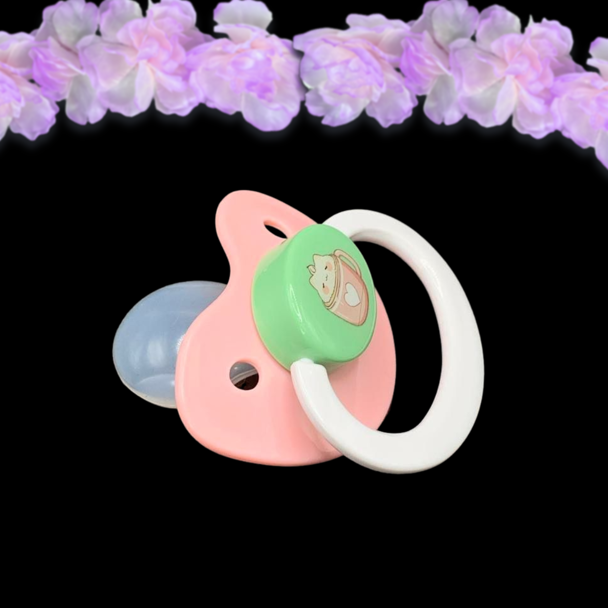 adult pacifier with pink shield, white handle and mint button. Center image of coffee mg with white heart and cat foam