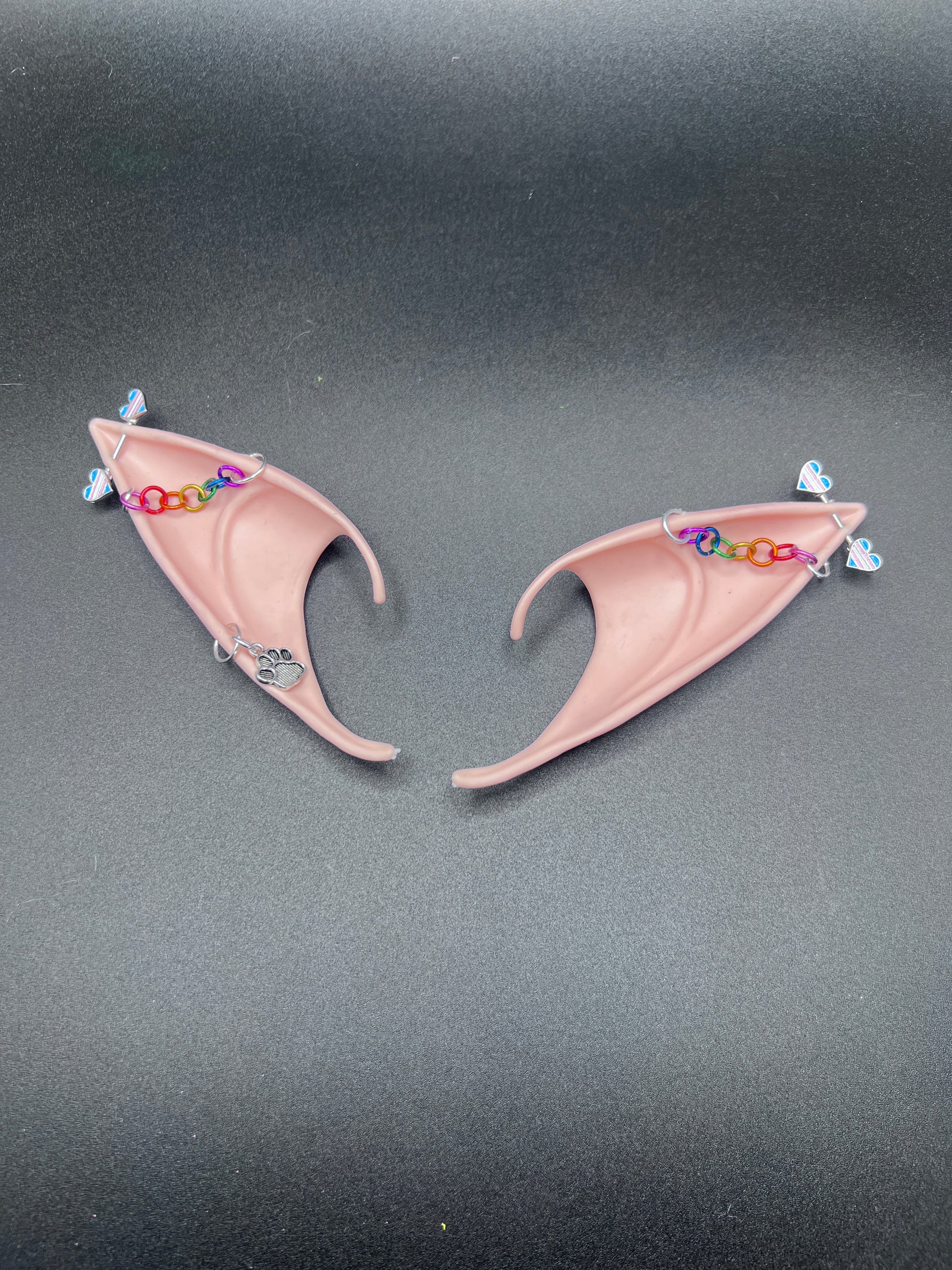 Pair of pink fairy elf ears with colorful chain on a dark background