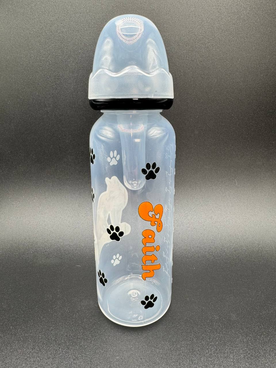 Clear adult baby bottle with paw prints and 'Faith' text on a gray background