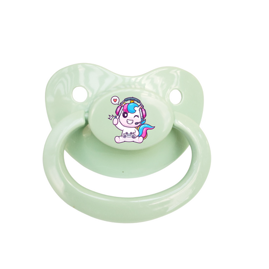 Light green adult pacifier with a unicorn playing video games and winking on the button on a white background