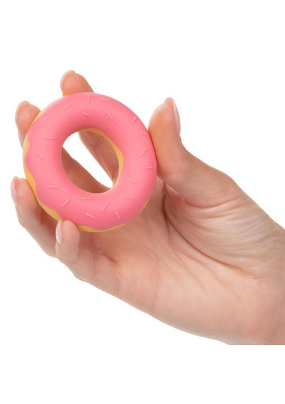 Hand holding a fun pink donut-shaped penis ring for adult men and sissies