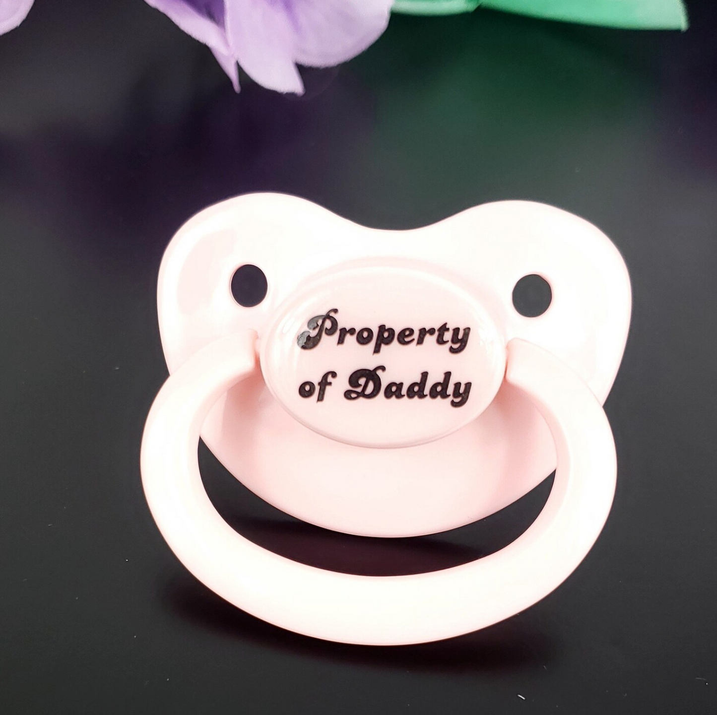 Baby Pink adult pacifier with bold text saying "Property of Daddy" in the center, adding a playful and loving sentiment. 