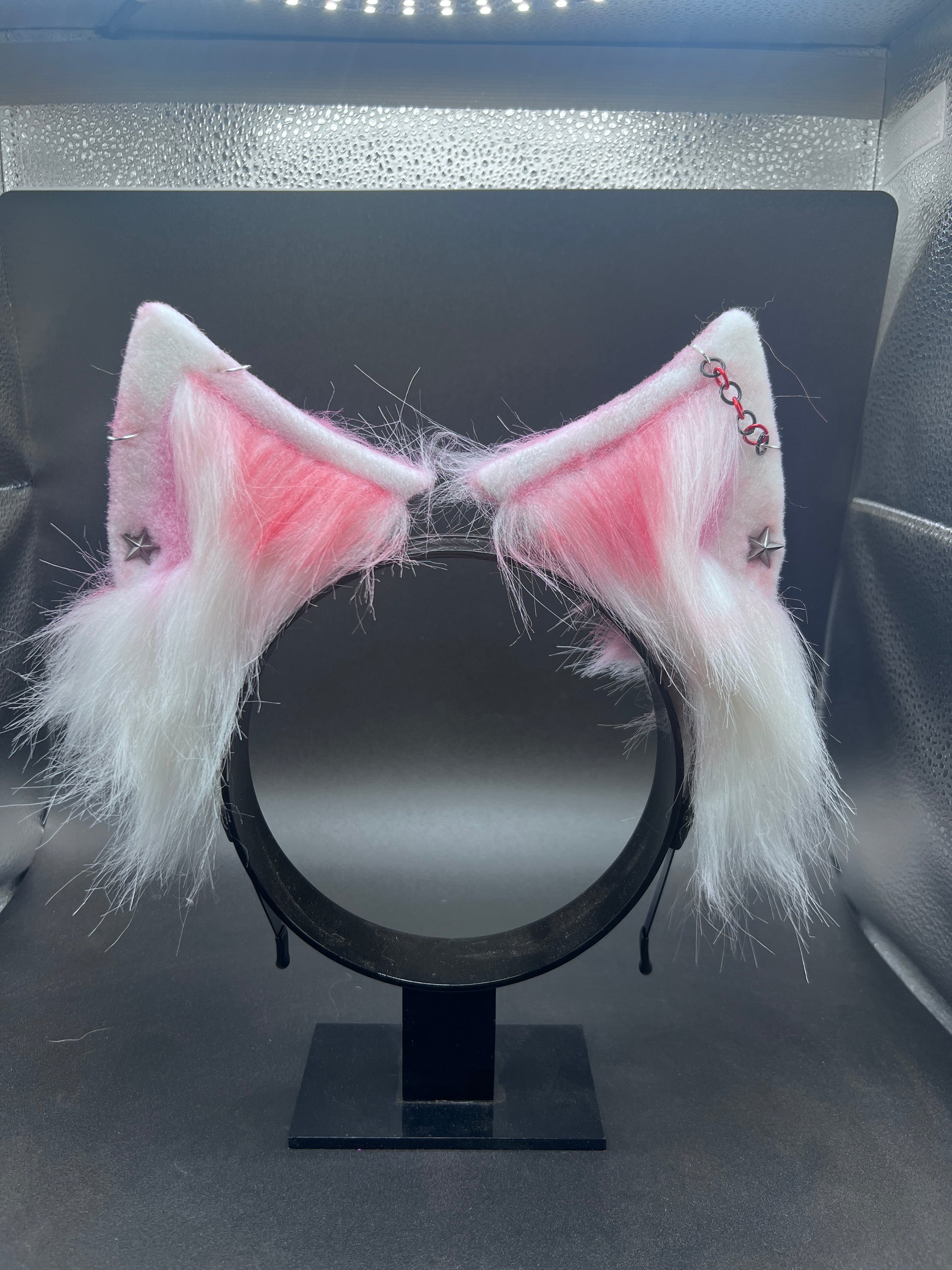 Cat ears with pink interior on a stand against a dark background