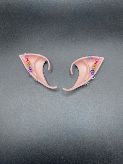 Pair of tan elf ears with colorful chain on a gray background