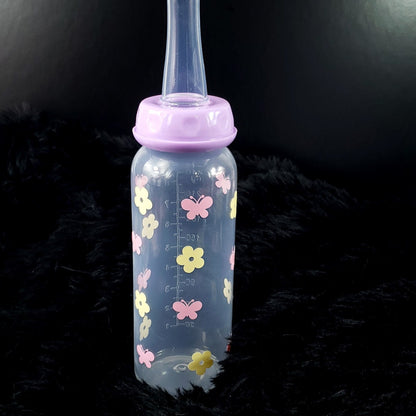 An 8oz adult baby bottle featuring a charming design with yellow flowers and pink butterflies, creating a whimsical and cheerful nature-inspired theme.