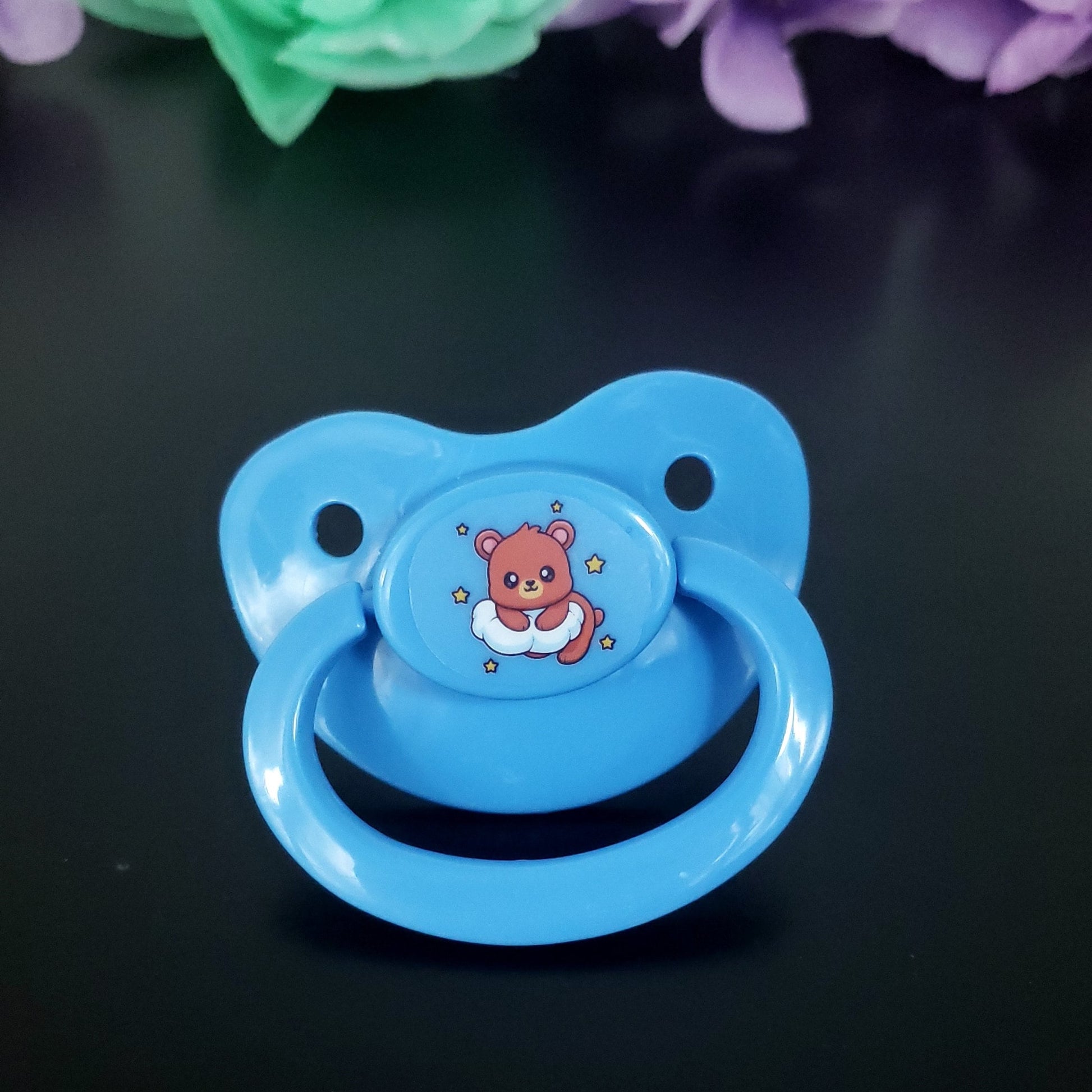 baby blue adult pacifier with bear laying on a cloud surrounded by stars on the center button