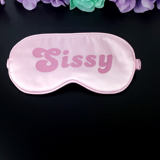 A pink blindfold with the word 'SISSY' printed in bold letters, designed for adult sensory play and role-playing.