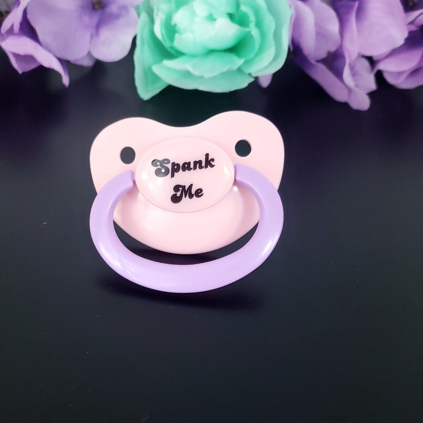 pastel adult pacifier with the text "Spank me" in the center