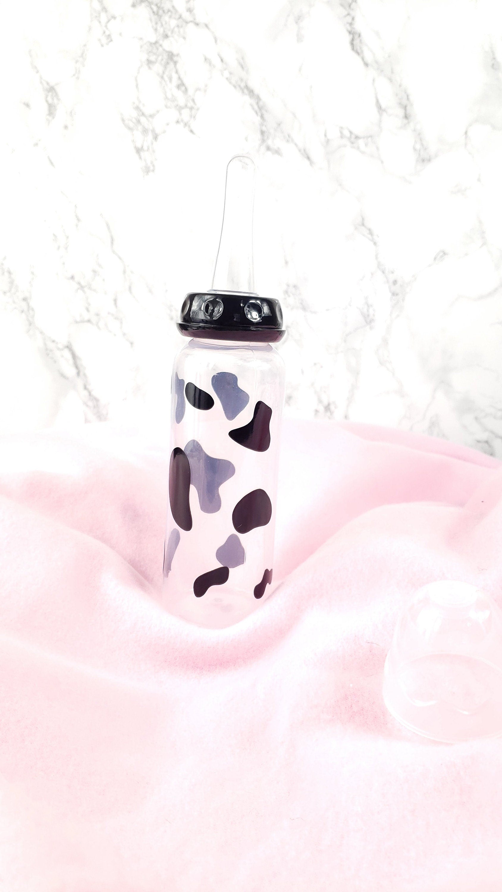 An 8oz adult baby bottle featuring a bold black cow spots pattern, creating a fun and farm-inspired design.