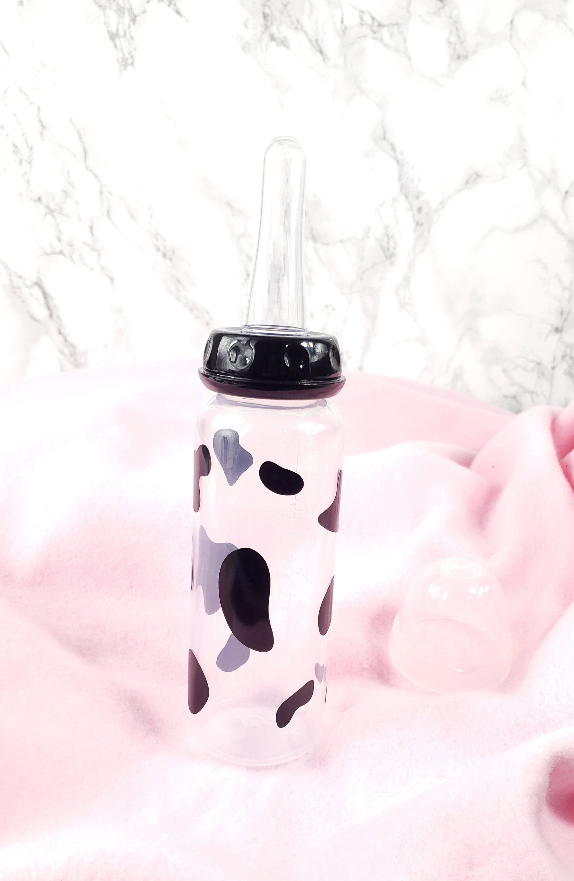 An 8oz adult baby bottle featuring a bold black cow spots pattern, creating a fun and farm-inspired design.