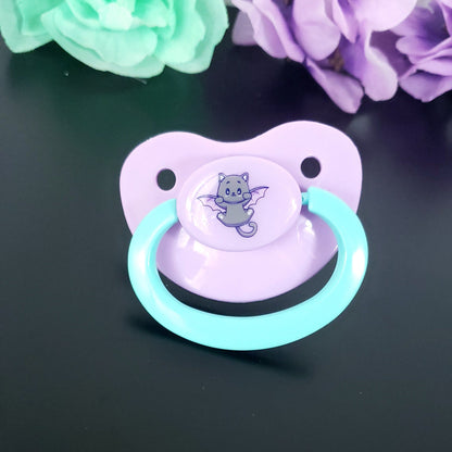 pastel purple adult pacifier with aqua handle featuring a fun and cute cat with bat wings