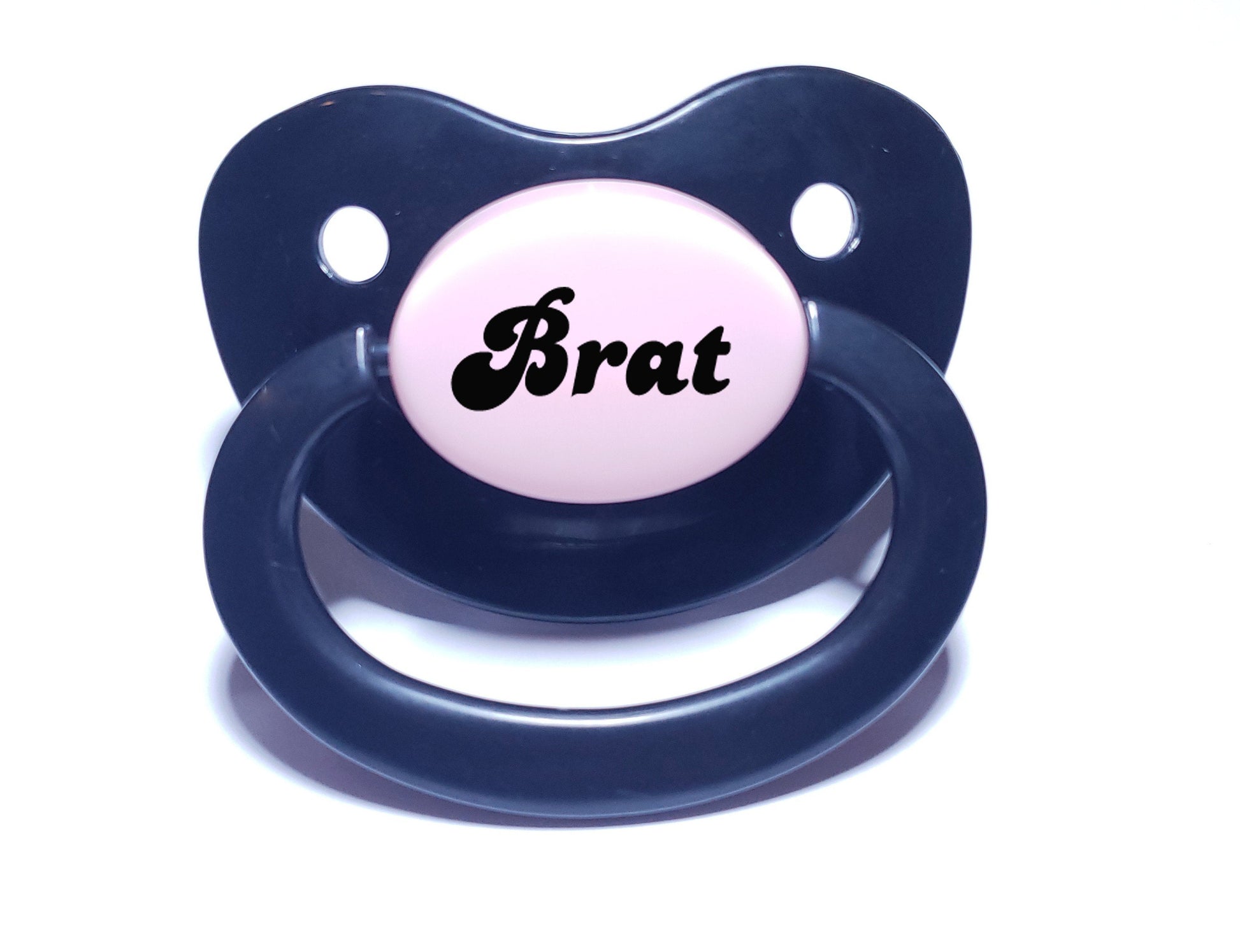 An adult pacifier featuring the word "Brat" boldly displayed in the center, designed for playful and cheeky self-expression.