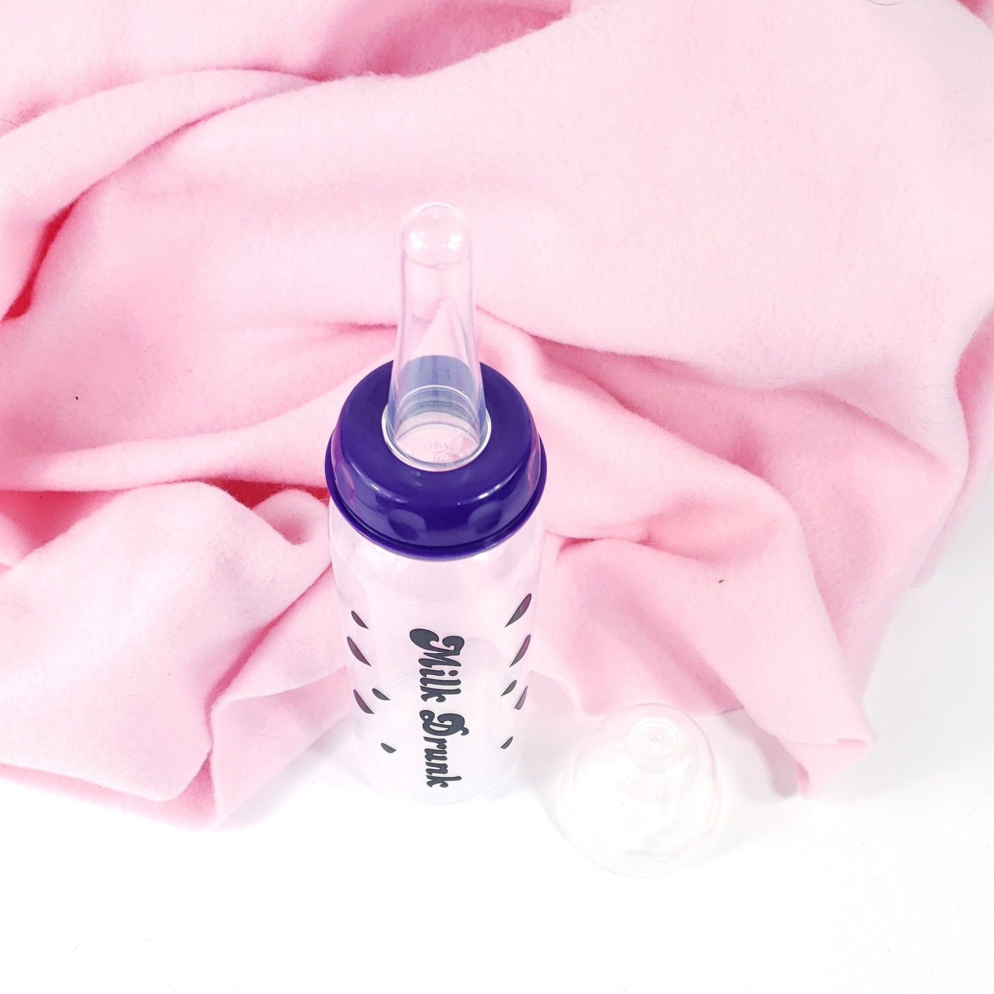 An 8oz adult baby bottle with the phrase "Milk Drunk" written in bold black text across with silhouette milk drops, offering a playful design.